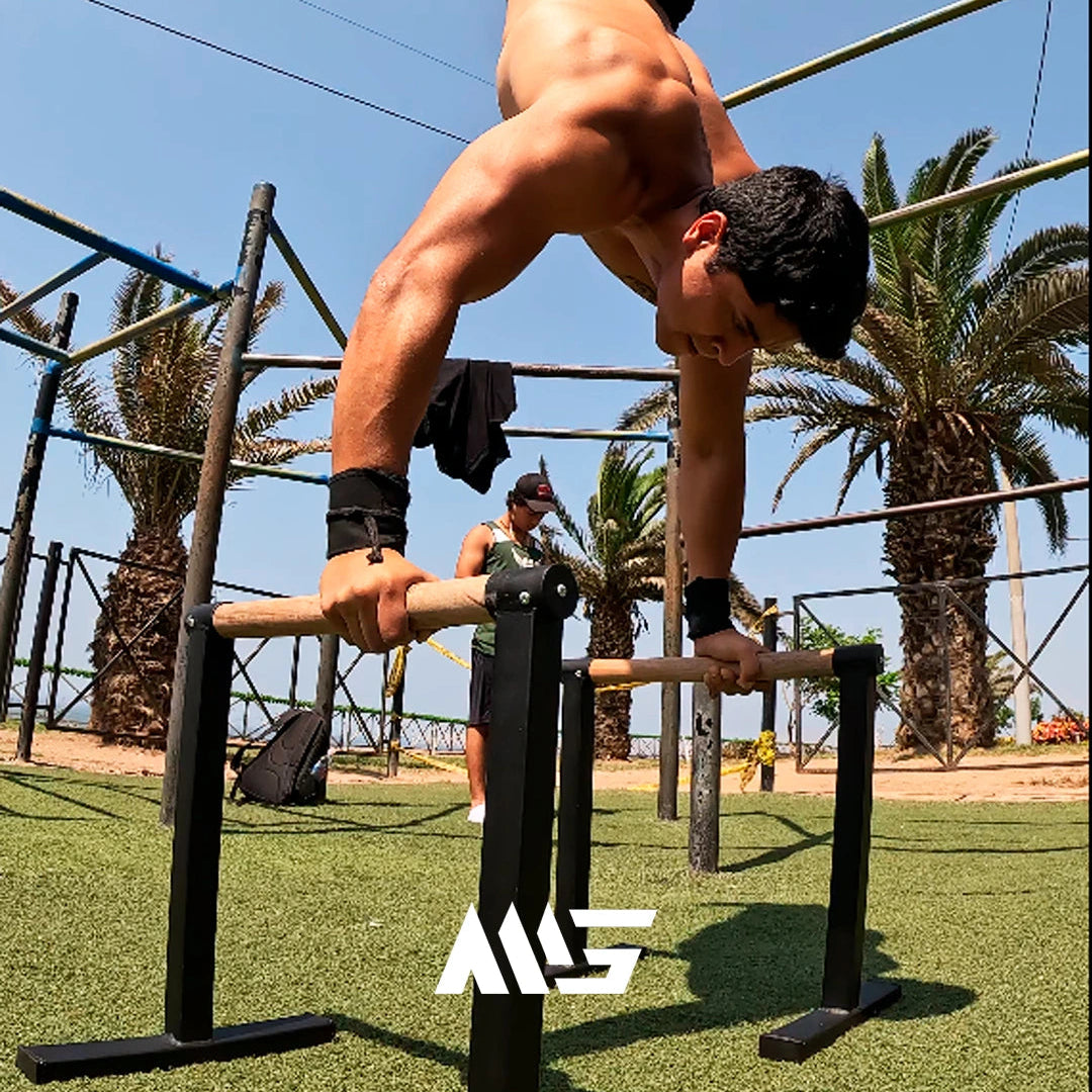Atleta usando paralelas street MiniGym para fondos en parque exterior.